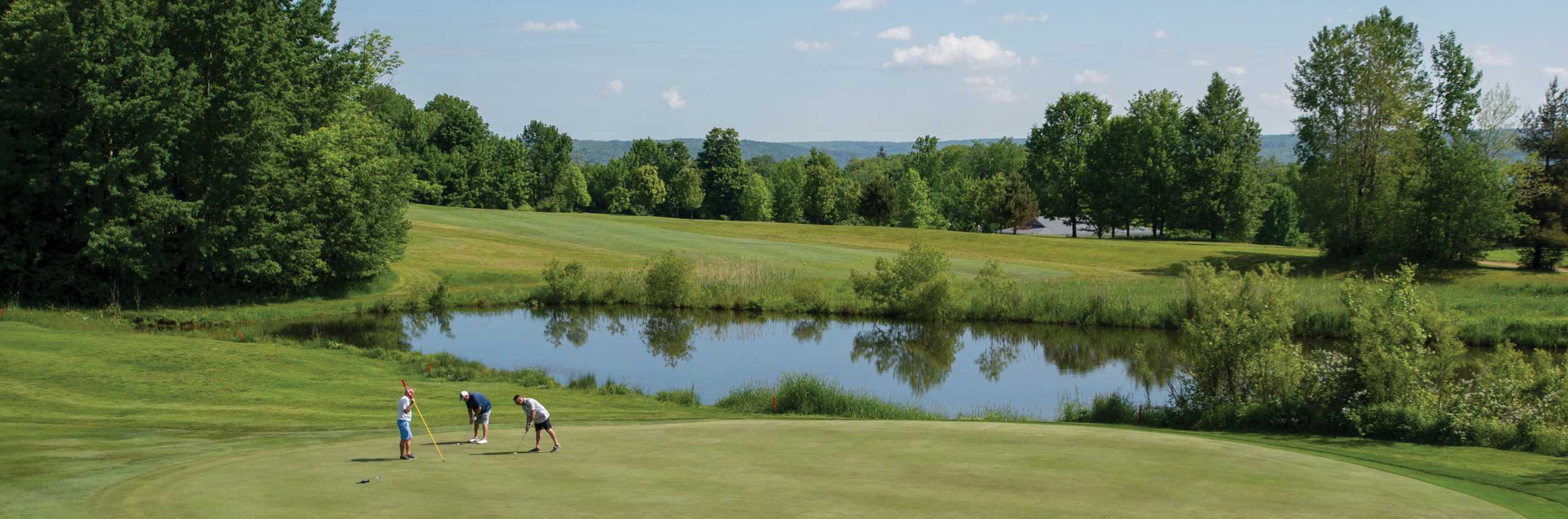 Three men golfing by a pond