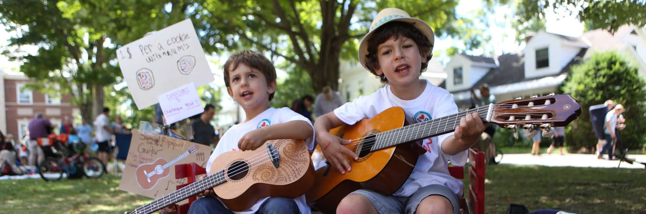 Two boys playing guitar to raise money for the Chautauqua Fund