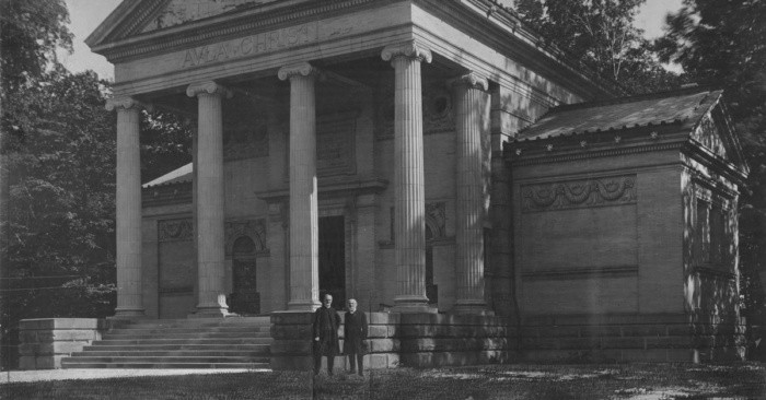 An old photo of two men standing in front of the Hall of Christ
