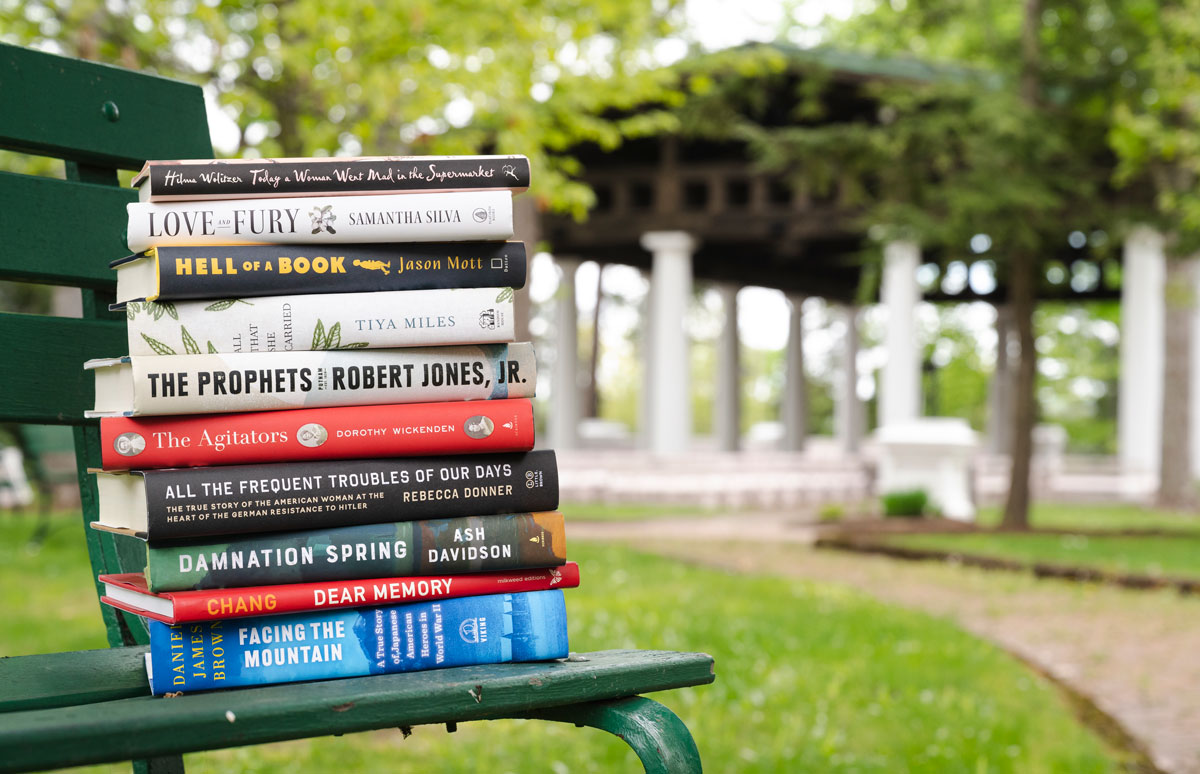 A stack of the 2022 Chautauqua Prize finalist books on a bench near the Hall of Philosophy