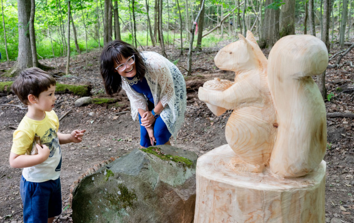 People looking at a wooden squirrel sculpture