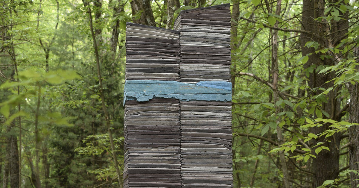 A sculpture of slates of rock stacked high with a blue section of stone in the middle.