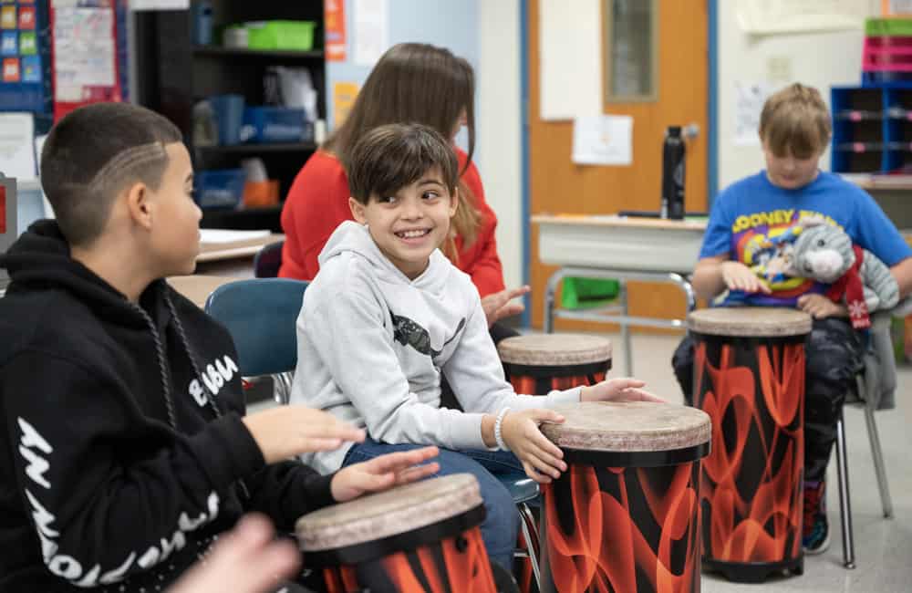 Middle school students playing drums in a classroom