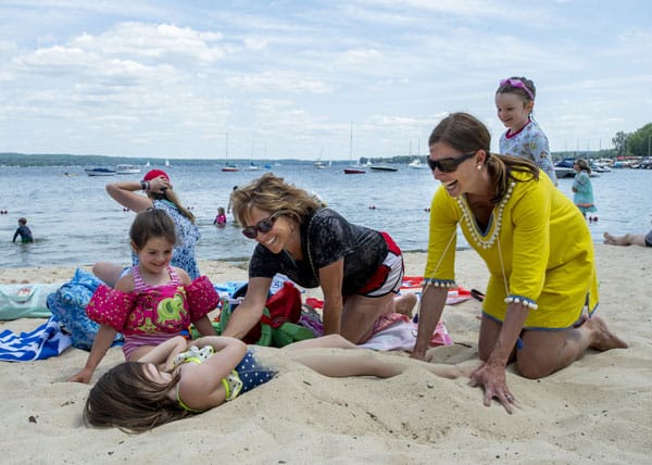 Two girls playing in the sand at Children's Beach with their mom and grandmother