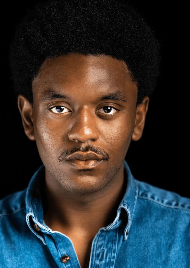 A headshot of Jauqcir LaFond in a denim button up with a black background