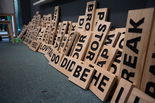Wooden word tiles lined up along a wall