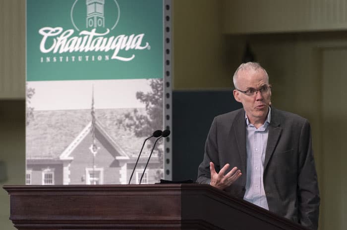 Bill McKibben at the podium giving a lecture and looking to the right