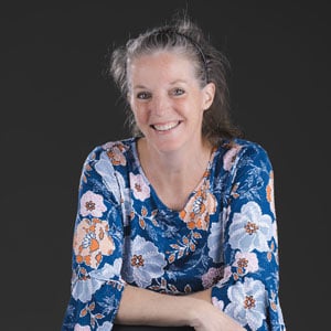 Betsy Burgeson in a blue floral blouse with a gray background