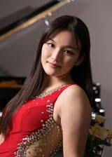 Seohee Yang sitting at a piano in a red dress