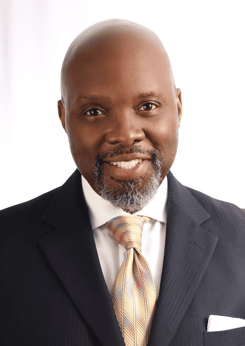 DeJeanette Horne headshot. He wears a multicolored tie, white shirt with a suit jacket.