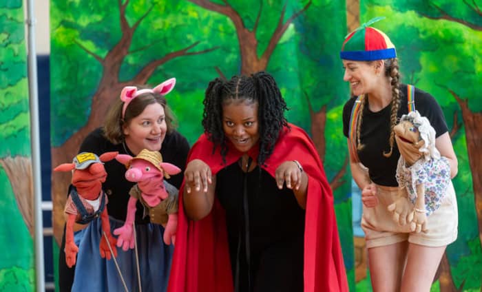 Opera singers holding puppets and performing