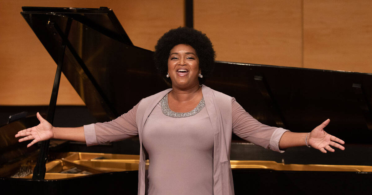 A woman singing in front of a piano