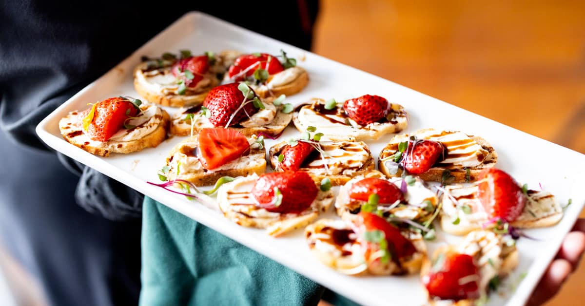 A server holding a plate of small bites