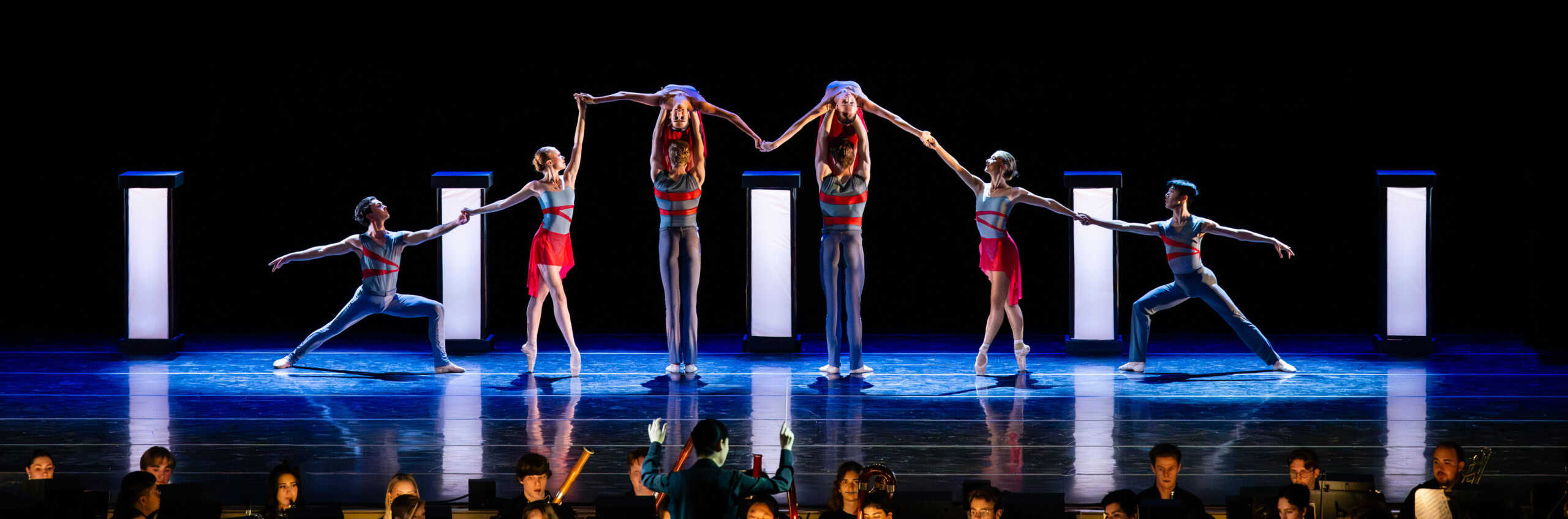 Dancers performing on stage with a live orchestra