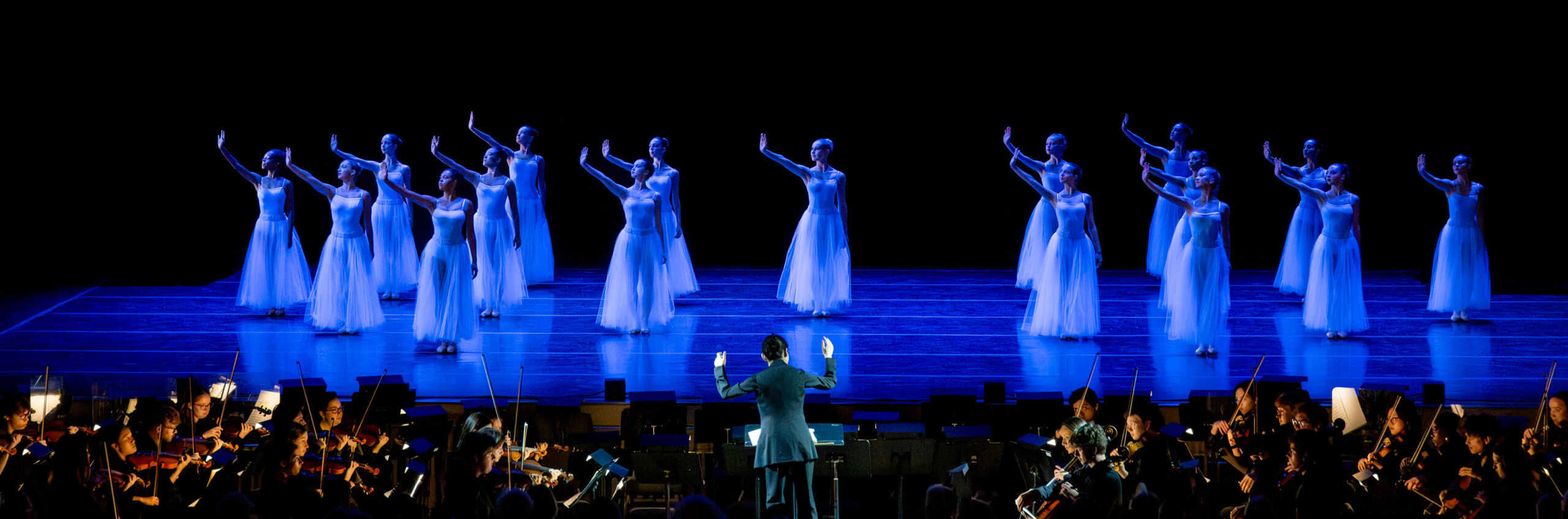 Dancers performing on stage with a live orchestra