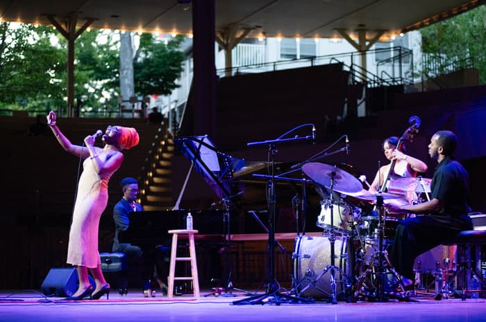 A woman singing with a band in the amphitheater