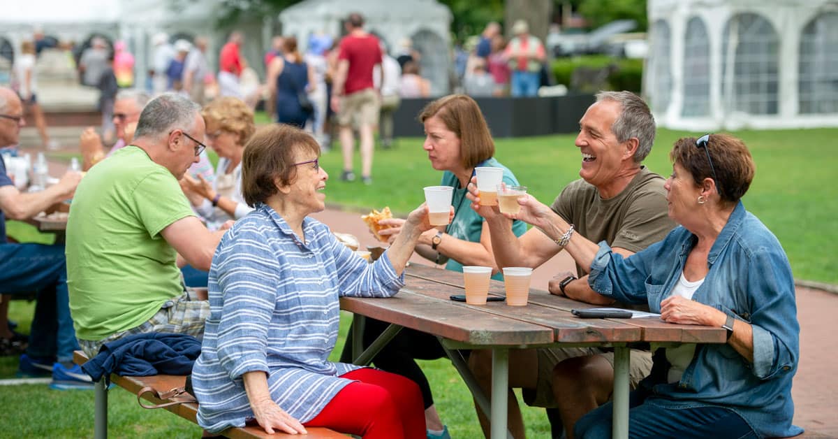 People drinking and eating together at a picnic table