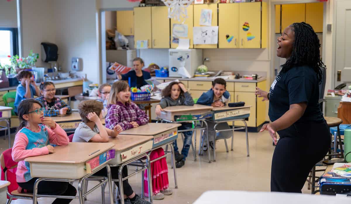 A woman singing to a classroom of children